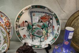 A Chinese Famille Jaune circular plate with figures playing a game.