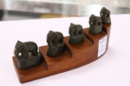 A graduated set of five small bronze elephants on a stepped wood base.