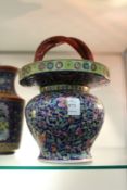 A Chinese floral decorated pottery basket with entwined handle.