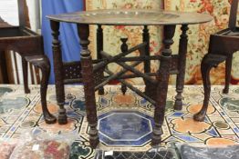 A large eastern engraved and painted circular copper tray table on folding stand.