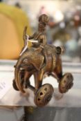 An Indian bronze toy modelled as a man riding a wheeled elephant.