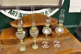 Two pairs of brass and copper oil lamps with cut glass reservoirs.
