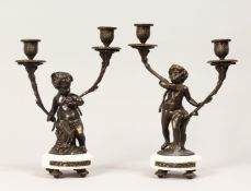 A PAIR OF FRENCH STYLE BRONZE CHERUBS AND MARBLE TWIN BRANCH CANDELABRAS. 12ins high.