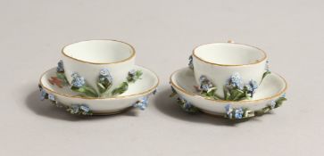 A MINIATURE PAIR OF 19TH CENTURY MEISSEN ENCRUSTED CUPS AND SAUCERS. Cross swords mark in blue