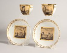 TWO PAIRS OF, POSSIBLY FRENCH, CUPS AND SAUCERS with panels of buildings.