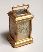 A MINIATURE BRASS CARRIAGE CLOCK with porcelain panel 3ins high.