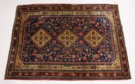 A PERSIAN QUASHQI CARPET, dark blue ground with three central diamond shaped medallions stylised