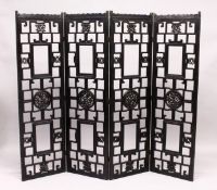 A CHINESE BLACK LACQUER FOUR SECTION CARVED WOOD FOLDING DRESSING SCREEN. Each panel 5ft 3ins high x