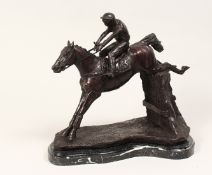 A CAST BRONZE GROUP DEPICTING A HORSE AND JOCKEY JUMPING A FENCE, on a marble base. 1ft 1ins high