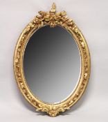 A DECORATIVE GILT FRAMED OVAL WALL MIRROR 3ft 7ins high x 2ft 6ins wide