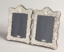 A PAIR OF SILVER REPOUSSE UPRIGHT PHOTOGRAPH FRAMES 8ins x 5.5ins