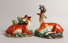 TWO LARGE STAFFORDSHIRE SEATED DEER with spots on rustic bases 7ins & 4.5ins.