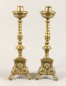 A PAIR OF 17TH CENTURY BRASS CANDLESTICKS on triangular bases 16ins high.
