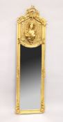 A TALL NARROW GILT FRAMED MIRROR, the upper panel decorated in relief with a female bust. 5ft