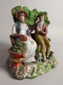 A GOOD PRATTWARE GROUP, A MAN AND WOMAN ON A BENCH a dog by their side 8ins high.