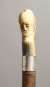 A GOOD 19TH CENTURY WALKING CANE with carved bone handle as a monkey and face, with silver band.