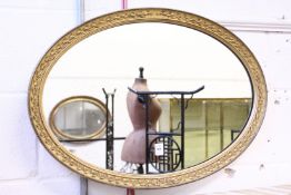 A gilt framed oval mirror.