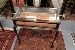 A mahogany bijouterie table on carved cabriole legs united by stretchers.