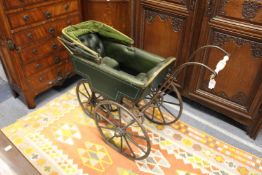 An unusual Victorian pram with wrought iron frame and green leather upholstery.