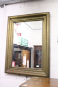 A wall mirror with embossed brass frame.