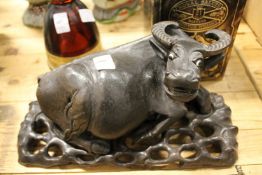 A Chinese carved wood model of a buffalo on a separate carved wood stand.