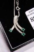 A 14ct white gold, diamond and emerald pendant and chain.