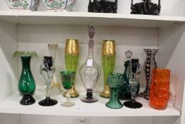 A good shelf of colourful glassware to include a Whitefriars orange glass bark vase.