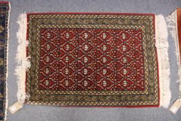 A small Persian rug, crimson ground with geometric design.
