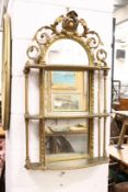 A decorative gilt framed mirror with open work cresting and three shelves.