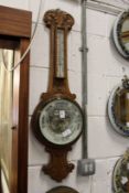 A carved oak cased barometer and thermometer.