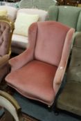 A pink draylon upholstered wing armchair.