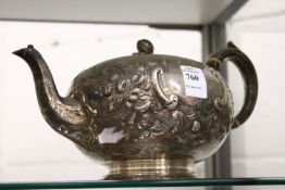 A Victorian silver teapot with embossed decoration.