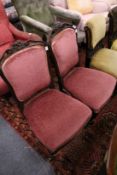 A pair of Victorian carved rosewood framed low chairs with upholstered backs and seats.