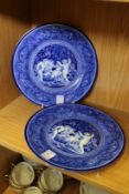A pair of blue and white plates decorated with cherubs.