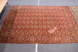 A large Persian Bokhara carpet (some wear and staining).