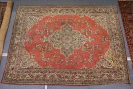 A large pink ground Persian design carpet with floral decoration.