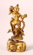 A SMALL INDIAN GILT BRONZE FIGURE, holding an item in its right hand, standing on a naturalistic