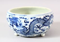 A CHINESE BLUE & WHITE PORCELAIN DRAGON BRUSH POT - with tripod feet, depicting dragons chasing