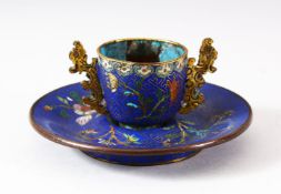 A CHINESE CLOISONNE TWIN HANDLE CUP AND SAUCER, decorated with floral sprays upon a geometric