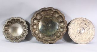 THREE INDIAN WHITE METAL EMBOSSED DISHES - each of varied design and size - 24cm - 34cm