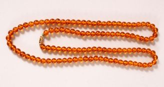 A CHINESE BEADED NECKLACE, possibly amber, each bead approx. 7mm.