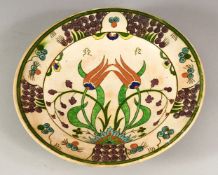AN IZNIK STYLE POTTERY DISH, possibly European, decorated with stylised flowers, 25cm diameter.