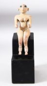 AN AFGHAN TERRACOTTA MODEL OF A SEATED FIGURE on a wooden stand, height on stand 23cm.