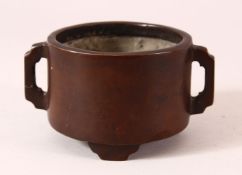 A CHINESE BRONZE TWIN HANDLED CENSER, on three feet with an impressed seal mark to base, 14cm