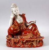 A CHINESE COPPER RED GLAZED PORCELAIN FIGURE OF GUANYIN - guanyin leaning upon a lion dog - the