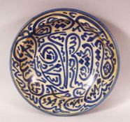 AN ISLAMIC CIRCULAR POTTERY BOWL, painted with stylised calligraphy, 22cm diameter.