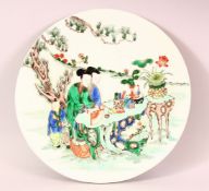 A CHINESE FAMILLE VERTE CIRCULAR PORCELAIN PLAQUE, depicting figures in a landscape, 29.5cm