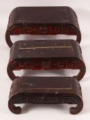 A GRADUATED SET OF THREE CHINESE HARDWOOD STANDS, each with curving ends and carved decoration,