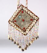AN ISLAMIC CEREMONIAL NECKLACE, the plaque with cowrie shell border, 15.5cm square.