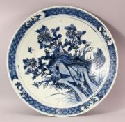 A LARGE CHINESE BLUE AND WHITE PORCELAIN CHARGER, central depicting a peacock amongst native
